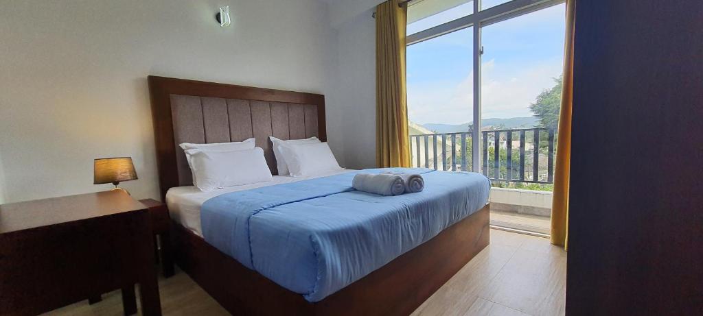 a bedroom with a bed and a large window at Green Lake View Condo Two Bed Room Apartment in Nuwara Eliya