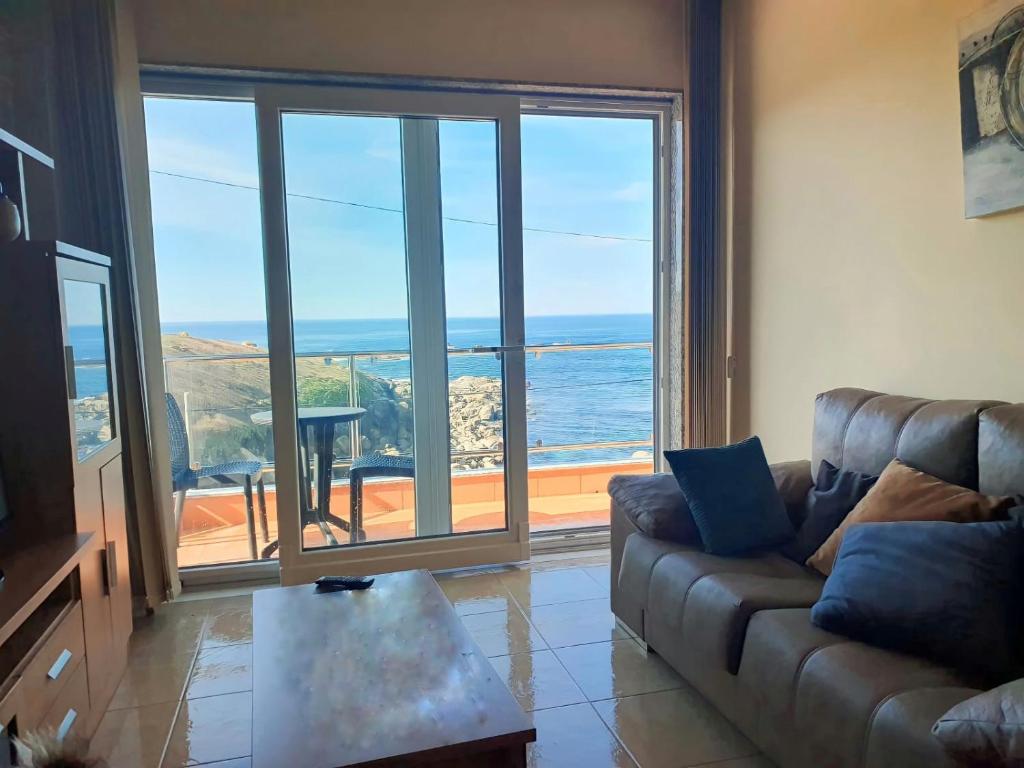 uma sala de estar com um sofá e vista para o oceano em Beiramar2 em Muxía