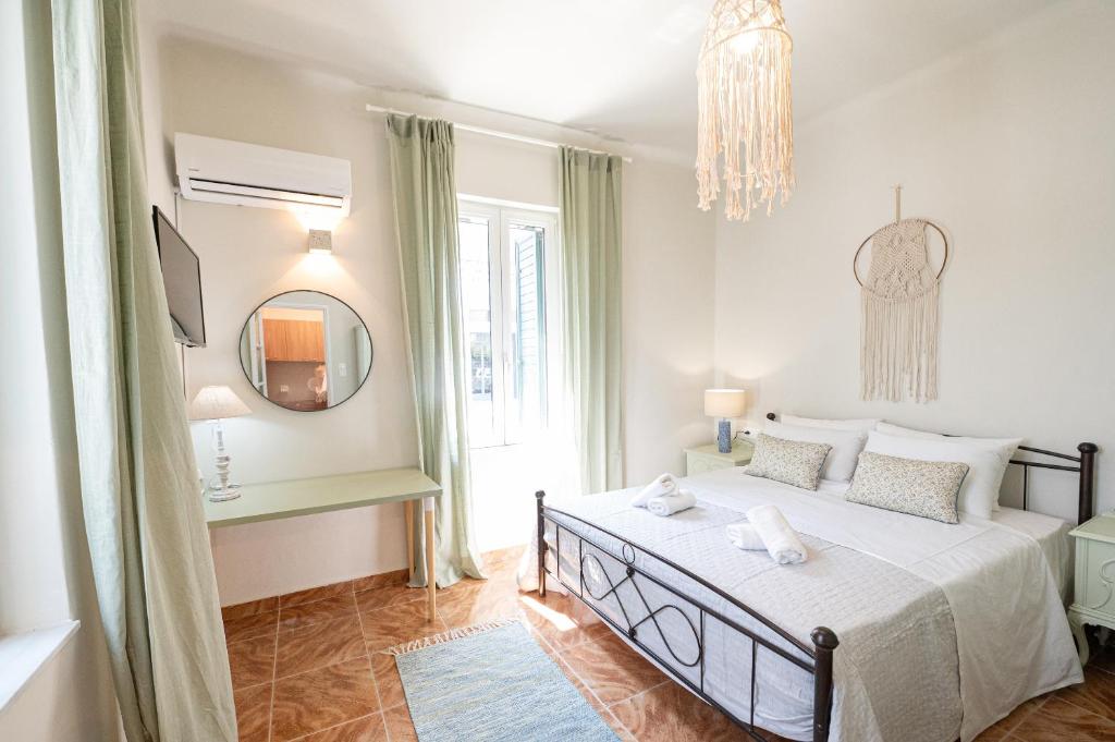 a white bedroom with a bed and a mirror at Sunny yard apartments in Poros