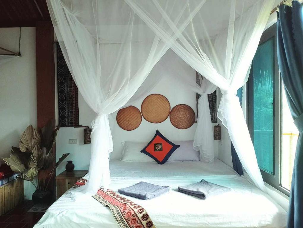 1 dormitorio con 1 cama blanca con dosel en Vu Linh Palm House Homestay - Bungalow en Yen Bai