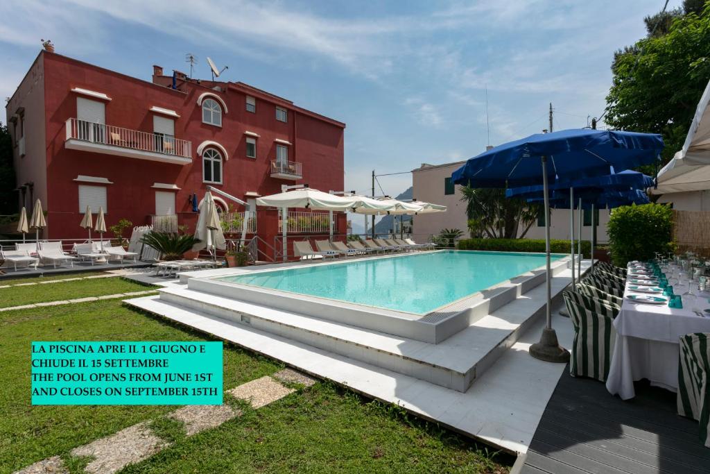 a swimming pool in front of a red building at Palatium Mari in Capri
