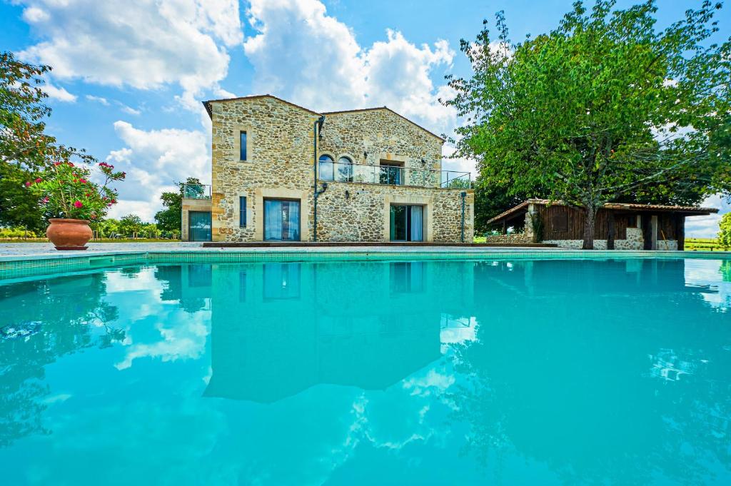 una grande piscina di fronte a una casa in pietra di Domaine de Badine, Bordeaux centre 15mn a Saint-Sulpice-et-Cameyrac