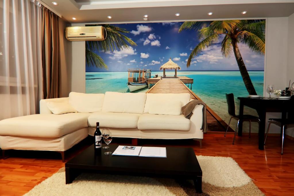 ティミショアラにあるMonique's 2 rooms Apartmentの白いソファとビーチの壁画が備わるリビングルーム