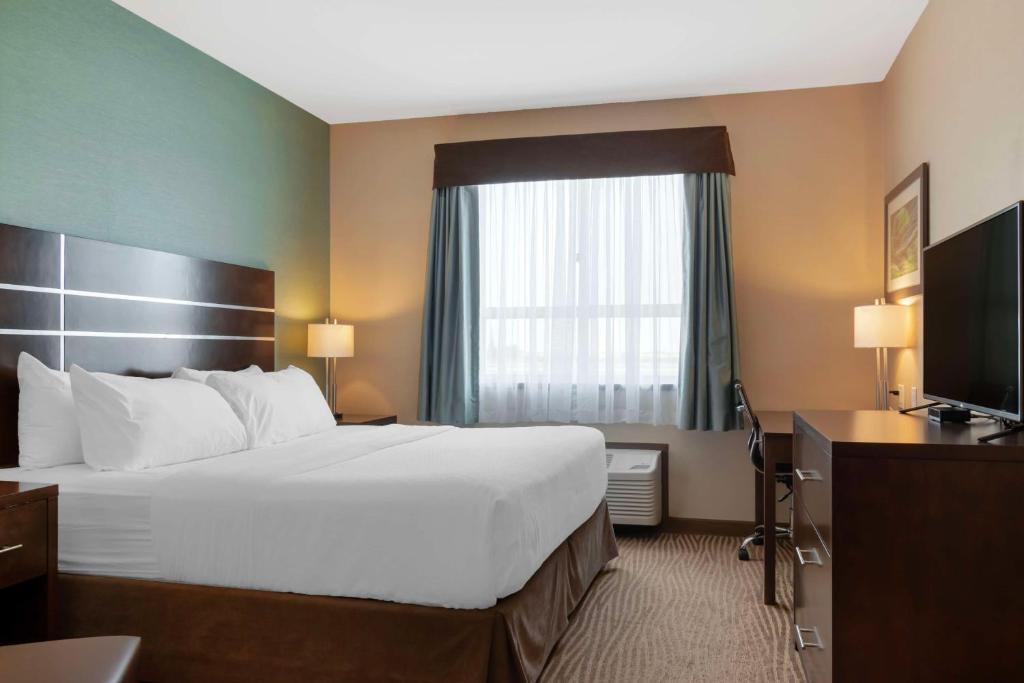 a hotel room with a large bed and a television at Best Western Plus Moosomin Hotel in Moosomin