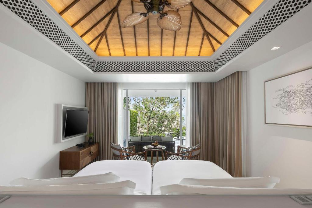 a bedroom with a ceiling fan and a living room at Banyan Tree Krabi in Tab Kaek Beach