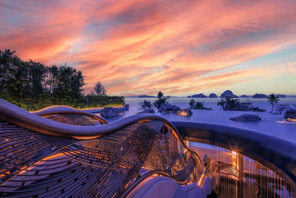 a bench with a sunset in the background at Banyan Tree Krabi in Tab Kaek Beach