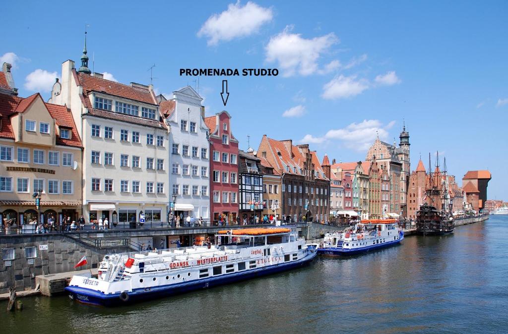 two boats are docked on a river in a city at Promenada Studio in Gdańsk