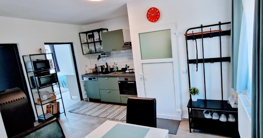 a kitchen with a red clock on the wall and a door at Innerpeace Vendégház in Galyatető