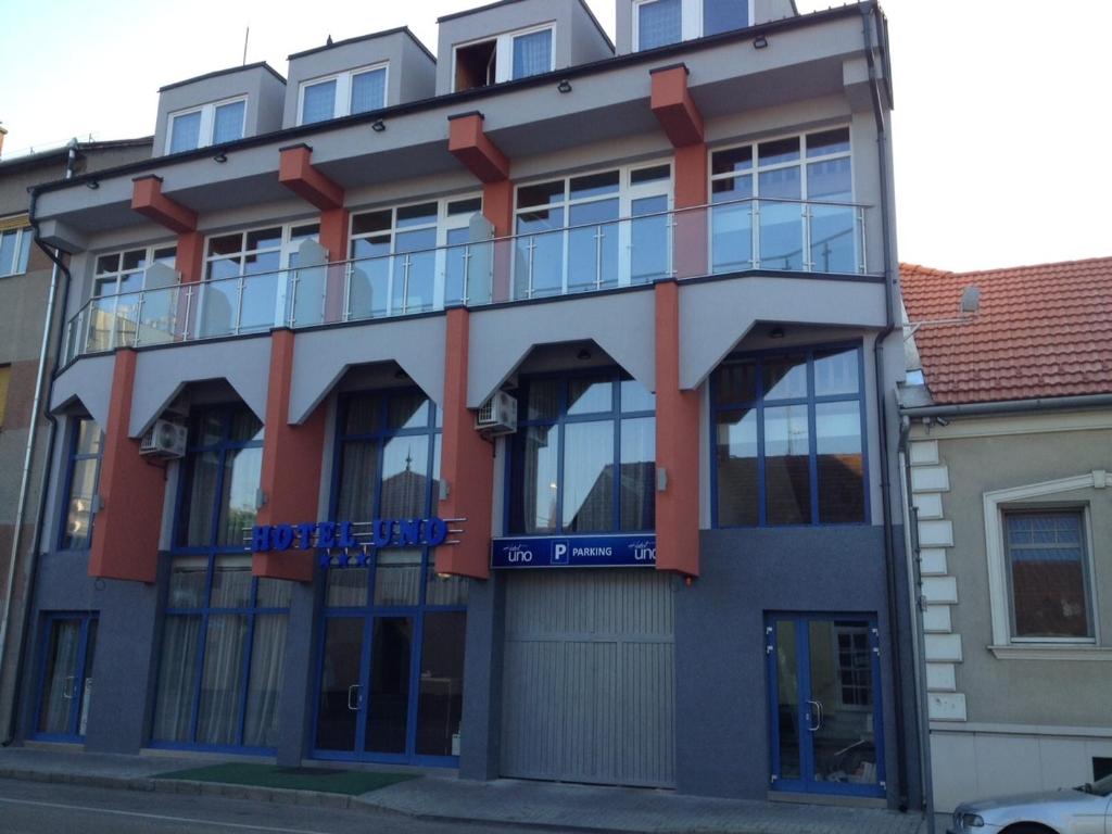 a building with a blue sign on the side of it at Hotel Uno in Kecskemét