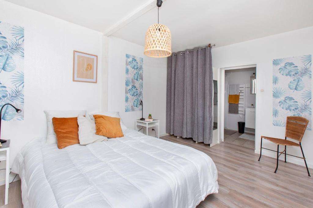 a white bedroom with a large bed and a chair at La Risle - Appartement spacieux in Brionne