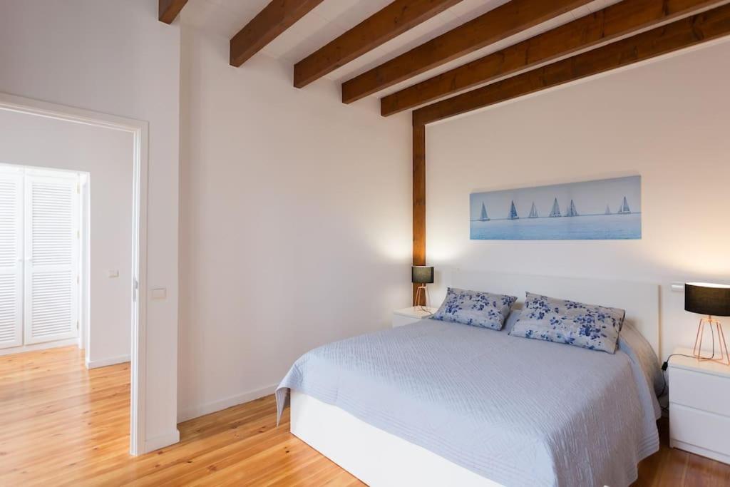 a white bedroom with a white bed and wooden floors at Casa Primavera - renovated duplex in city centre in Funchal