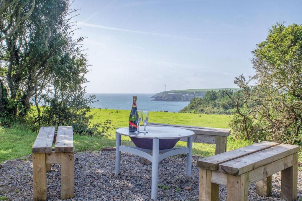 una mesa de picnic con 2 bancos y una botella de vino en Haven View - 1 Bedroom Shepherds Hut - St Ishmaels, en Saint Ishmaels