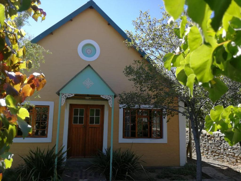 a small yellow house with a brown door at Loveable Karoo Cottages in Fraserburg