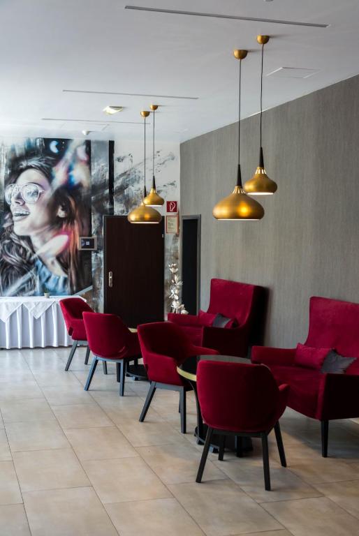 een eetkamer met rode stoelen en een schilderij aan de muur bij Best Western Plus Plaza Hotel Graz in Graz