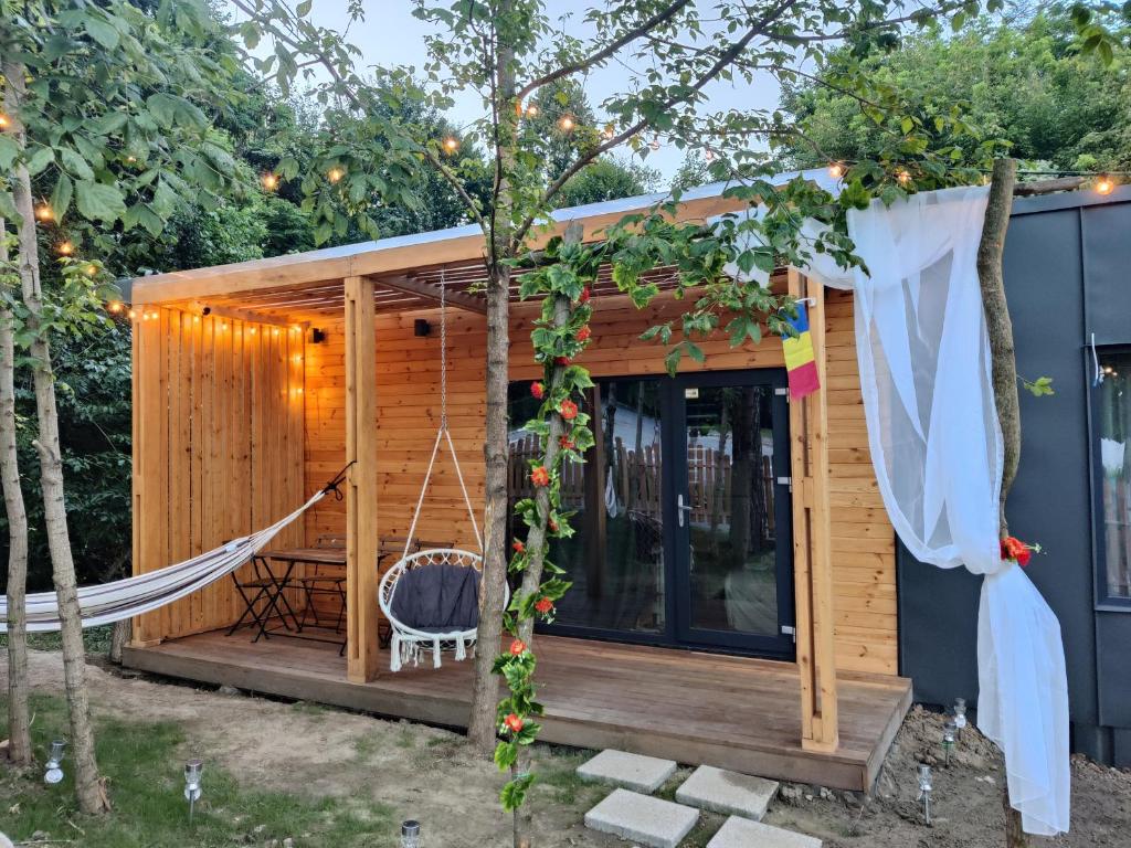 a tiny house with a hammock in the yard at Kub Baile Govora in Băile Govora