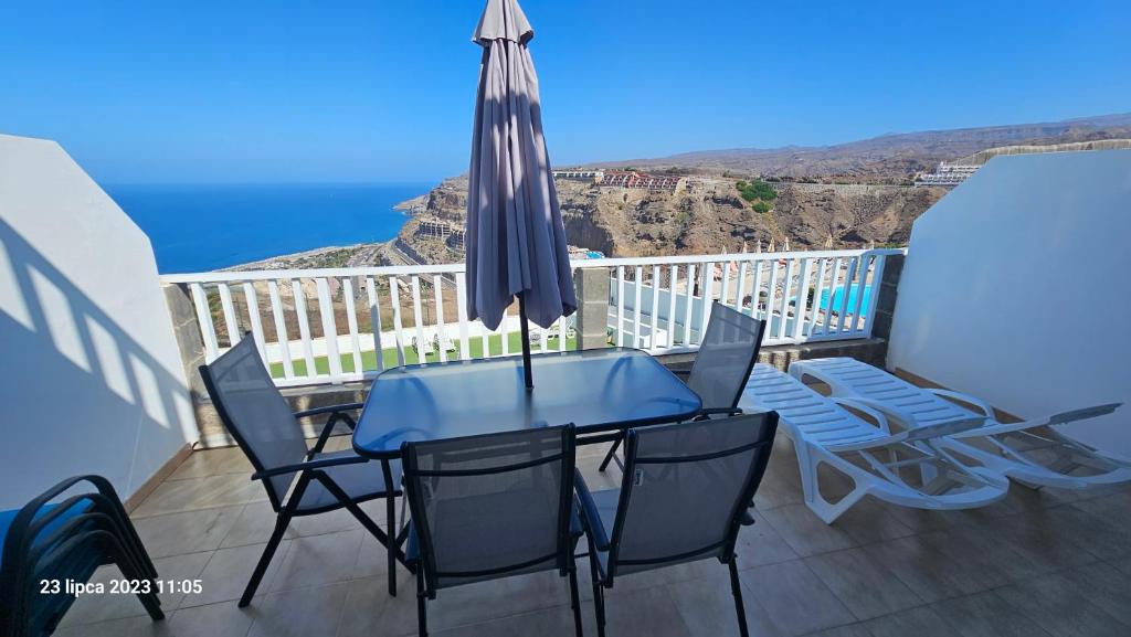 a table with chairs and an umbrella on a balcony at Puerto Rico Top Teide and Amadores View in Puerto Rico de Gran Canaria
