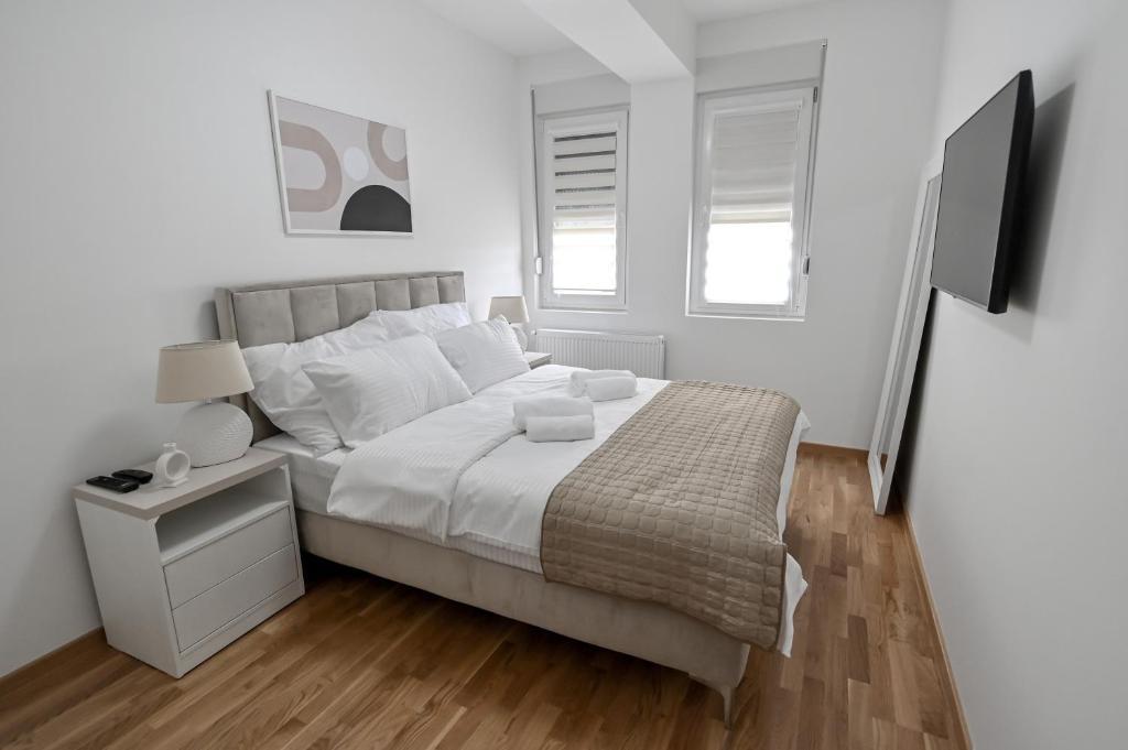 ein weißes Schlafzimmer mit einem großen Bett und einem TV in der Unterkunft Porto lux in Aranđelovac