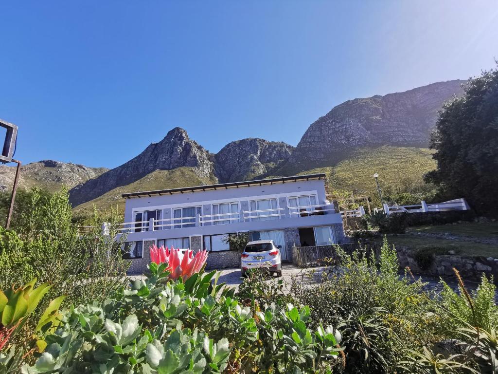 a building with a car parked in front of a mountain at Oceanscape in Bettyʼs Bay