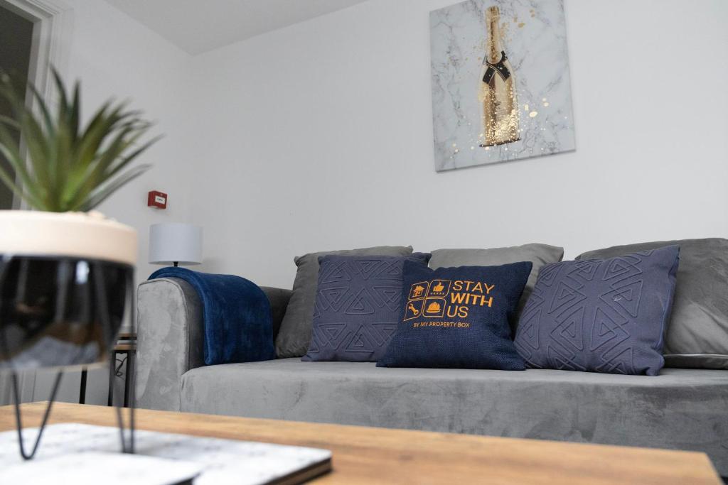 sala de estar con sofá gris y almohadas azules en Stylish Comfort 4-Bed on Church Road, Sleeps 4 en Stockton-on-Tees