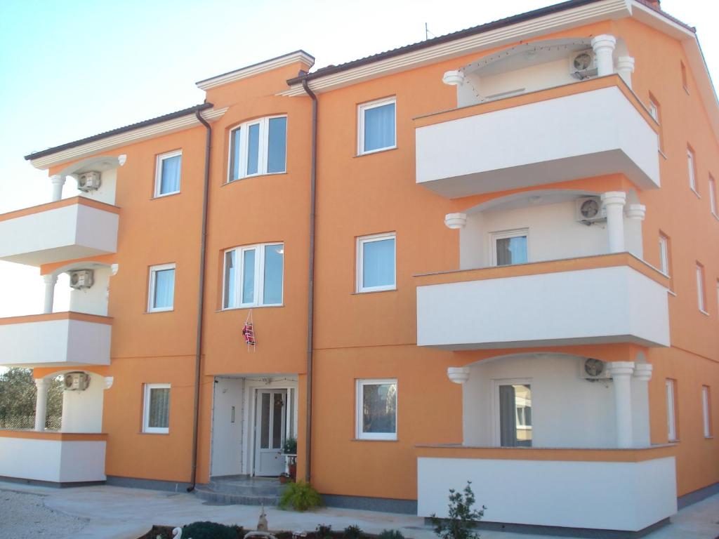 un edificio arancione con balconi bianchi di Apartments Buzleta a Fažana