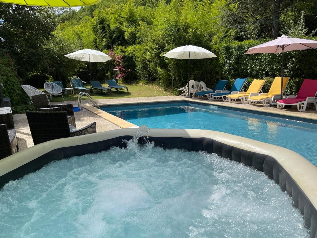 una gran piscina con sillas y sombrillas en un patio en Le jardin d'Eden, en Valojoulx