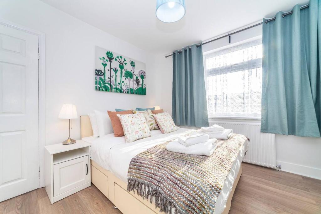 a bedroom with a bed and a window with blue curtains at 2-Bedroom Apartment in Greater London: Explore and Relax in Enfield