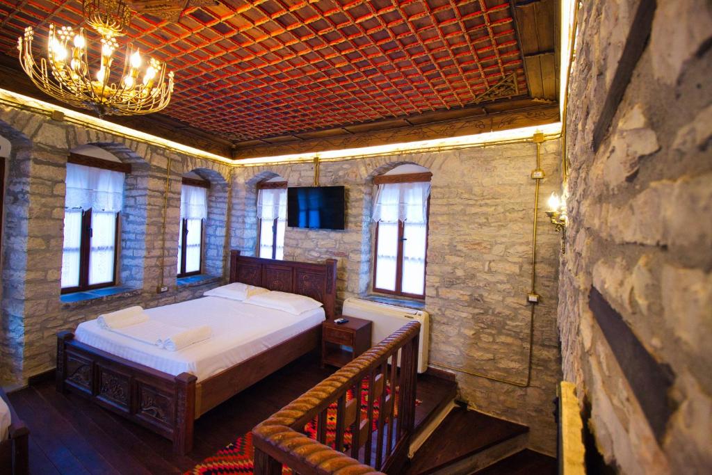 een slaapkamer met een bed en een kroonluchter bij Duplex Apartment KANDILE in Gjirokastër