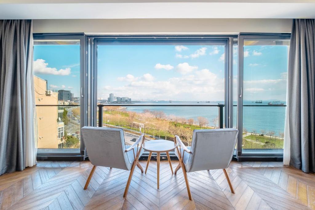 jadalnia ze stołem i krzesłami oraz dużymi oknami w obiekcie Homie Suites - Newly Built Seaside Apartments on Bakırköy Shore w Stambule
