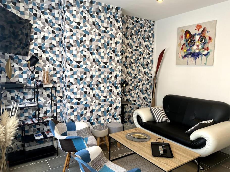 Una sala de estar con un sofá negro y una mesa. en Le P&#39;tit Cocon, en Calais