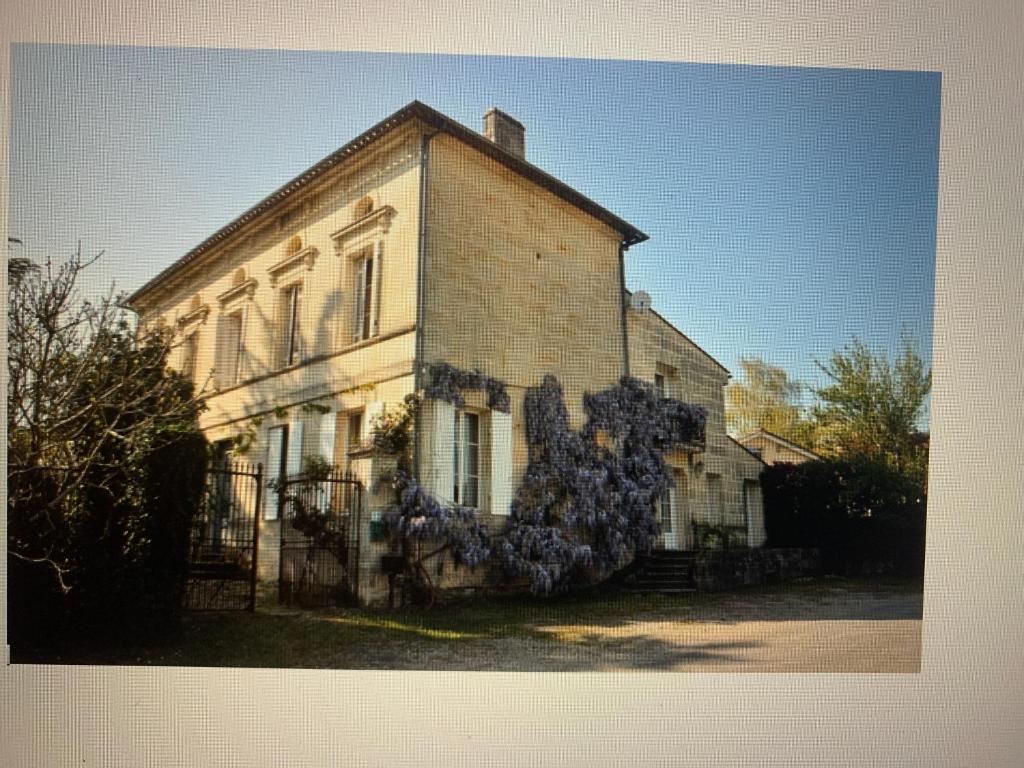 a large brick house with blue flowers on it at Buisson gîte et chambre d'hôte in Laruscade