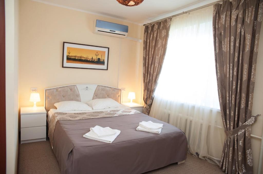 1 dormitorio con 1 cama y 2 toallas blancas en Mini-Hotel Skazka, en Dimitrovgrad
