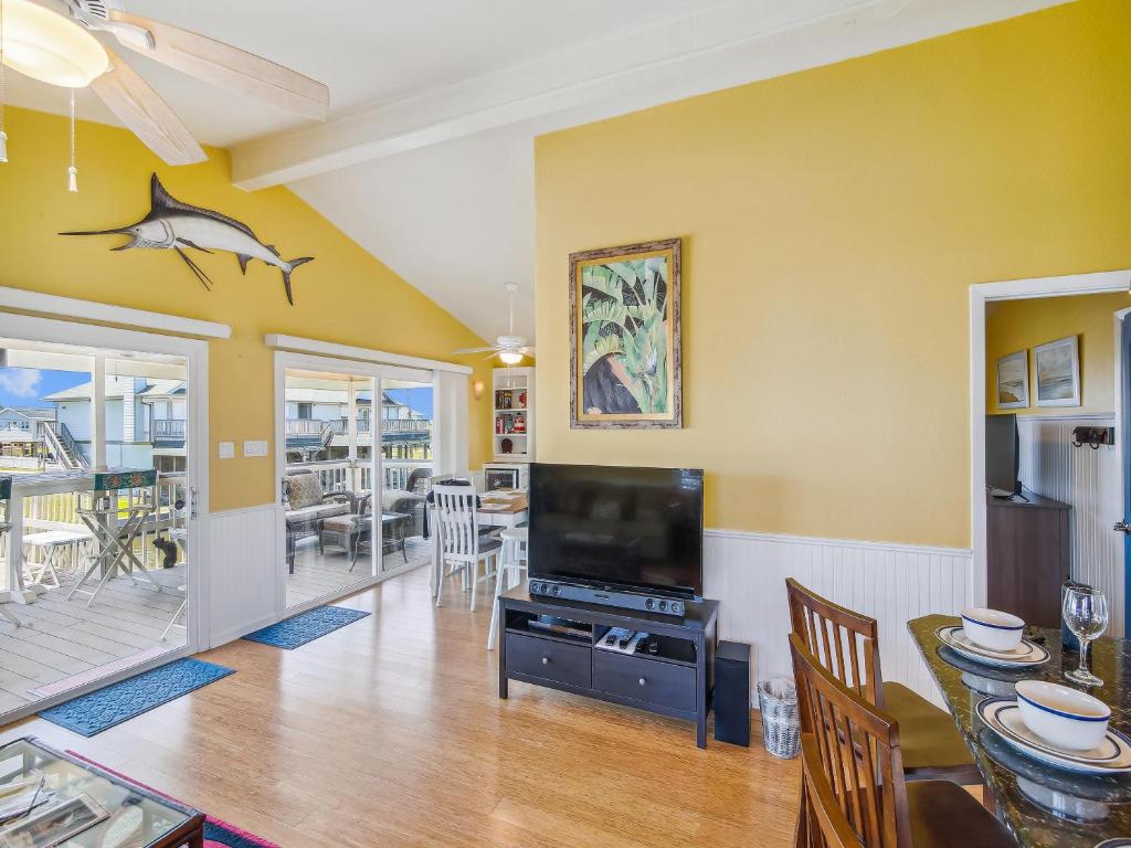 a dining room with a television and a dining table at Celestial Dreams in Galveston