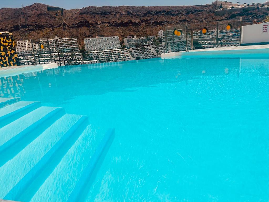 niebieski basen z krzesłami i górami w tle w obiekcie Relax & enjoy Cumana II Puerto Rico w mieście Puerto Rico de Gran Canaria