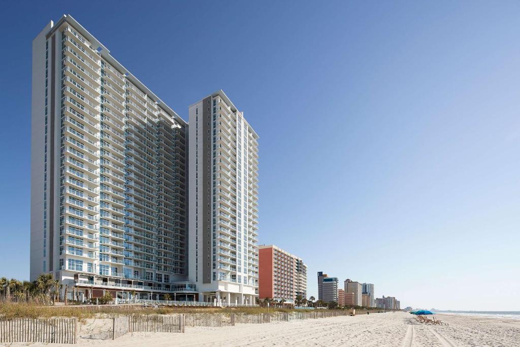 two tall buildings on the beach next to the ocean at Hilton Grand Vacations Club Ocean Enclave Myrtle Beach in Myrtle Beach