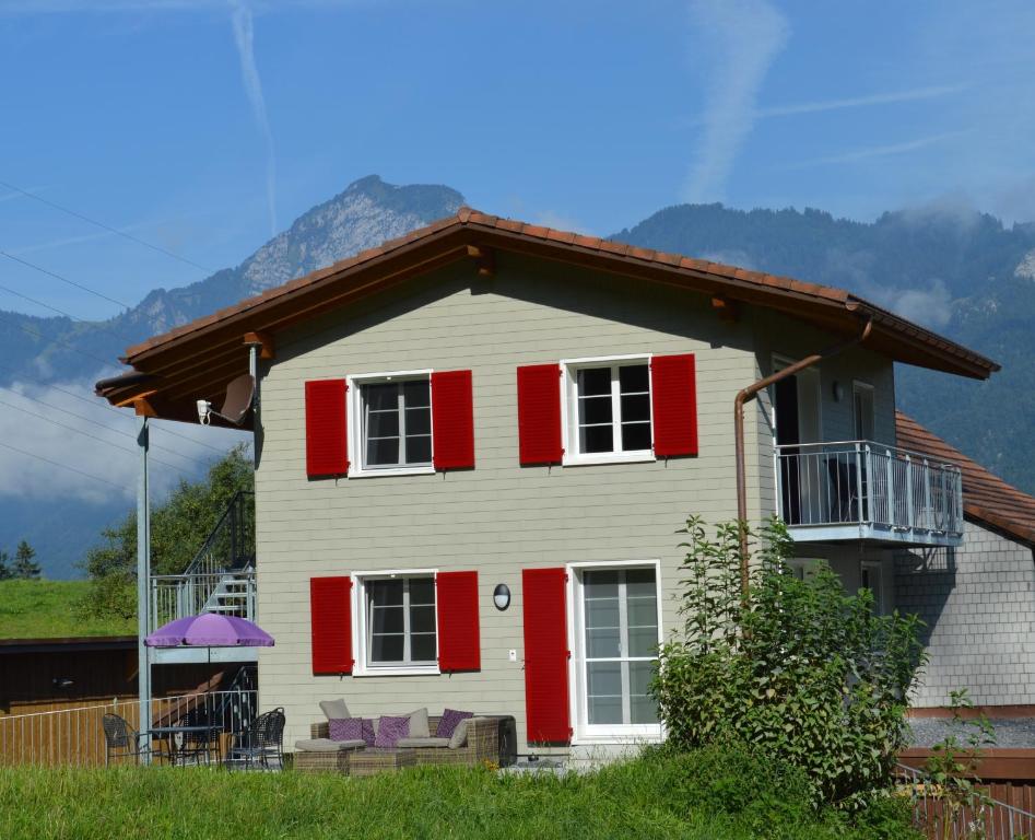 a white house with red shutters and a balcony at Ferienhaus Stockli in Brunnen