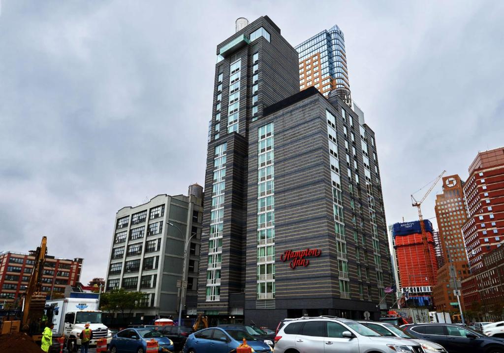 Un grand bâtiment avec des voitures garées dans un parking dans l'établissement Hampton Inn Brooklyn Downtown, à Brooklyn