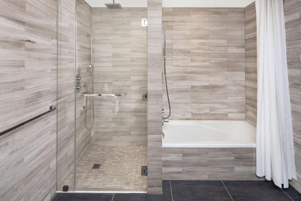 a bathroom with a tub and a shower with a shower curtain at Hilton Club The Quin New York in New York