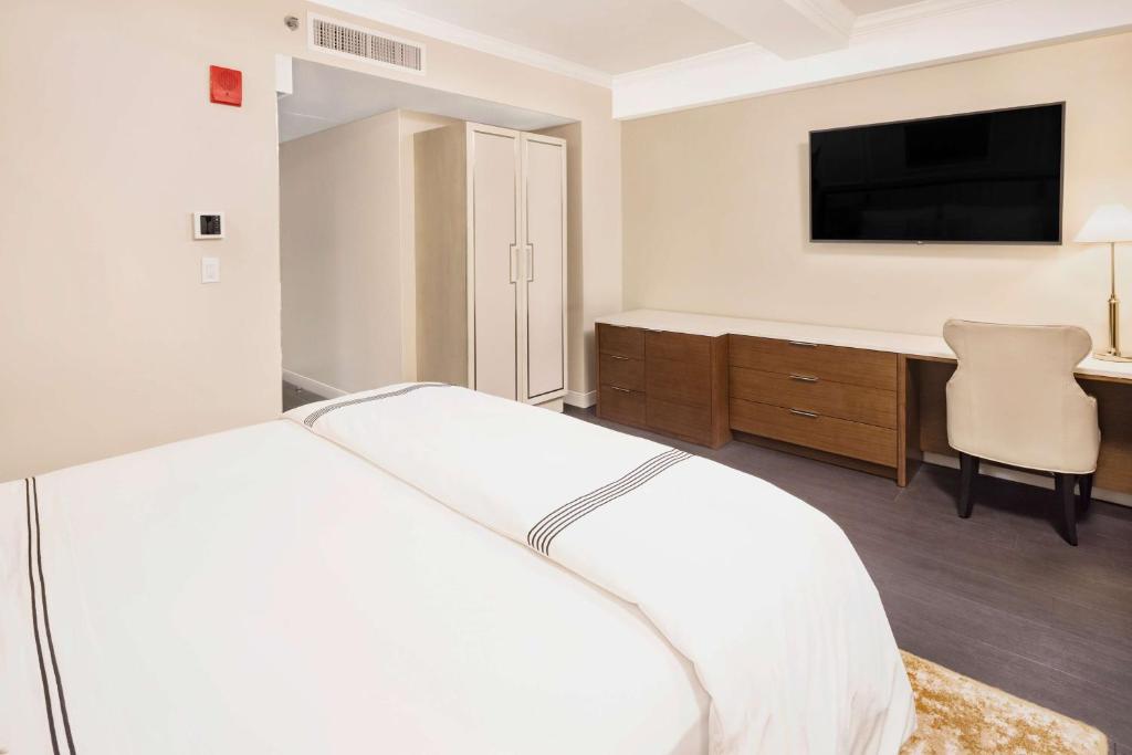a white bedroom with a bed and a desk at Hilton Club The Quin New York in New York