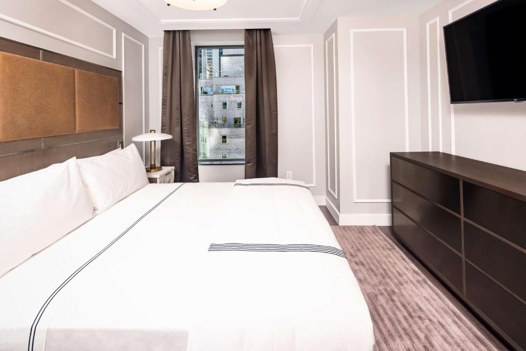 a bedroom with a large bed and a flat screen tv at Hilton Club The Quin New York in New York