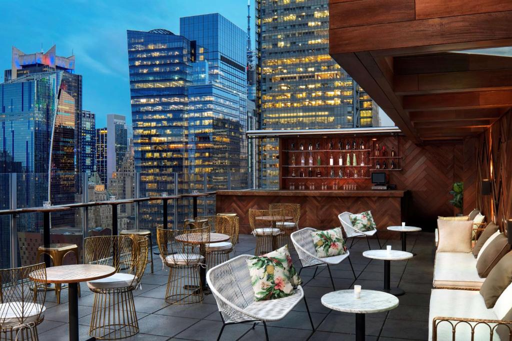 vista para um bar no último piso com mesas e cadeiras em Doubletree By Hilton New York Times Square West em Nova York