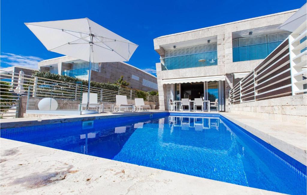 a house with a swimming pool and an umbrella at Villa Olea in Petrcane