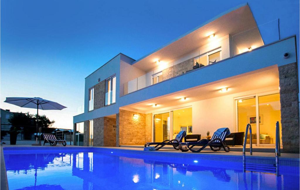 a house with a swimming pool in front of a house at Villa Crystal Blue in Rogoznica