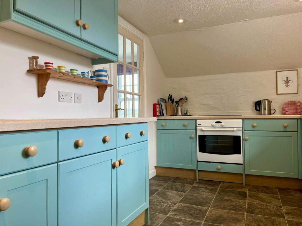a kitchen with blue cabinets and a stove at The Boathouse in Golant