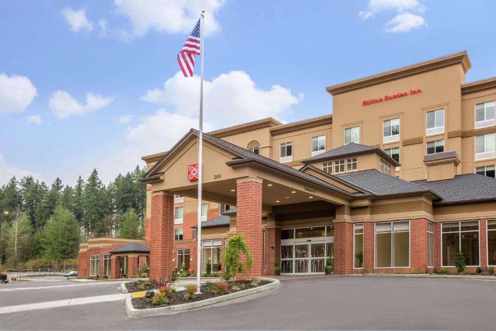 Hilton Garden Inn Olympia, WA في أولمبيا: فندق أمامه علم أمريكي