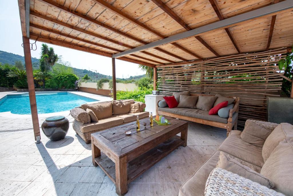 um pátio com sofás, uma mesa e uma piscina em 201 - Appartamento in Villa, Giardino e Piscina Privata em Lavagna