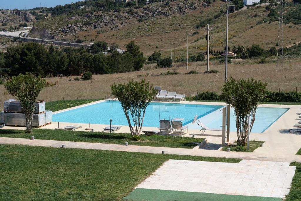 una gran piscina azul con árboles y una colina en Casa Mirea di Teti con piscina a Macari, en Macari