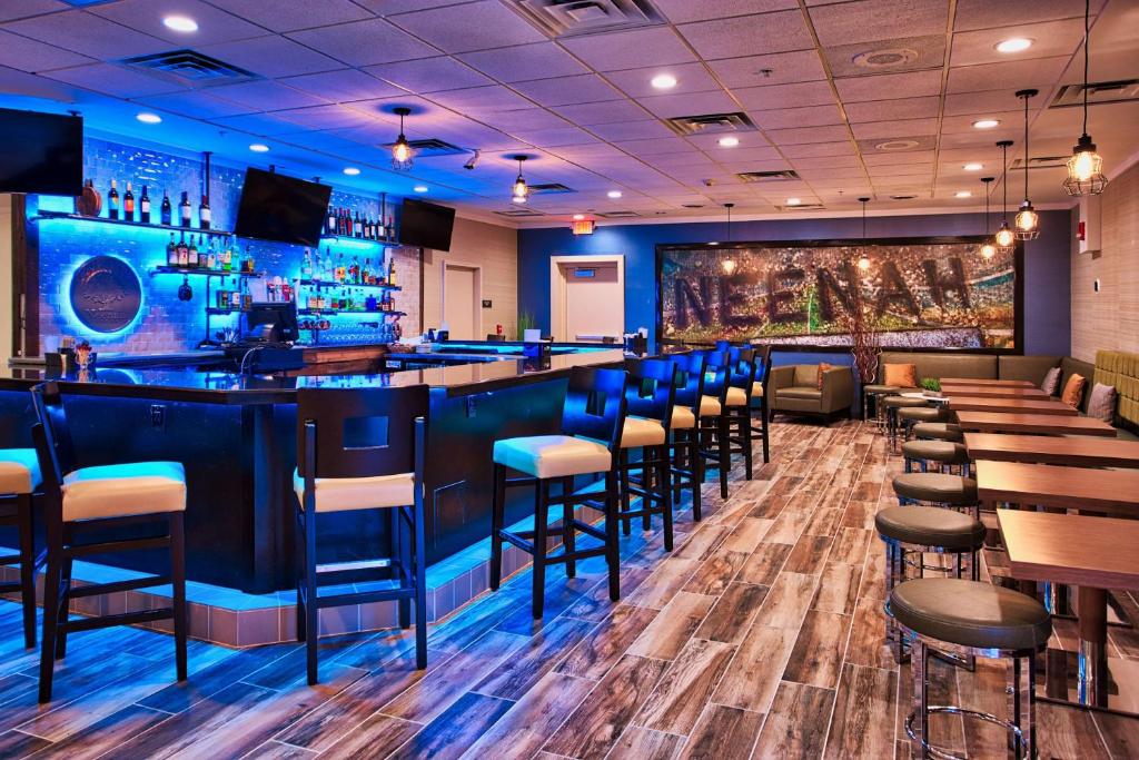 een bar in een restaurant met blauwe muren en krukken bij DoubleTree by Hilton Neenah in Neenah