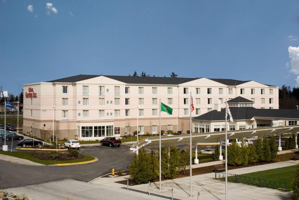 un gran edificio blanco con banderas en un estacionamiento en Hilton Garden Inn Seattle North/Everett en Mukilteo