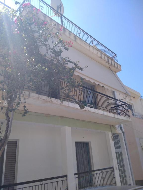 a white building with a balcony and a tree at Anastasia in Kyparissia