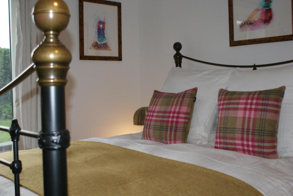 a bedroom with a bed with two plaid pillows at Keeper's Lodge in Rowlands Castle
